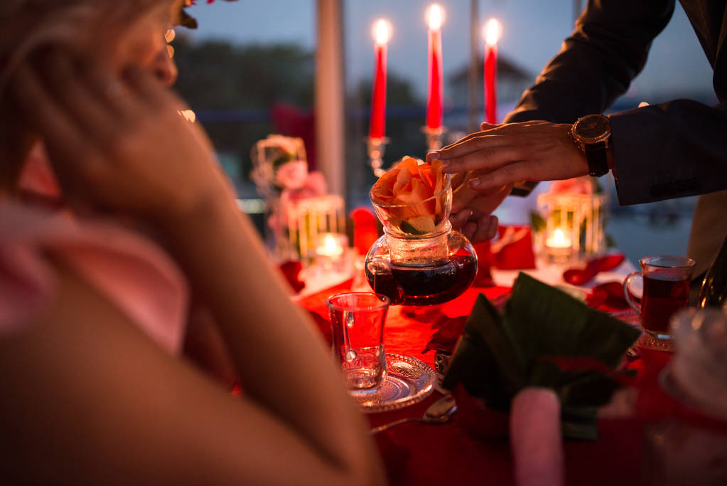 Facet wylewa herbatę w filiżance do swojej dziewczyny. Romantyczny stolik na kolację przy świecach. - Zdjęcie, obraz