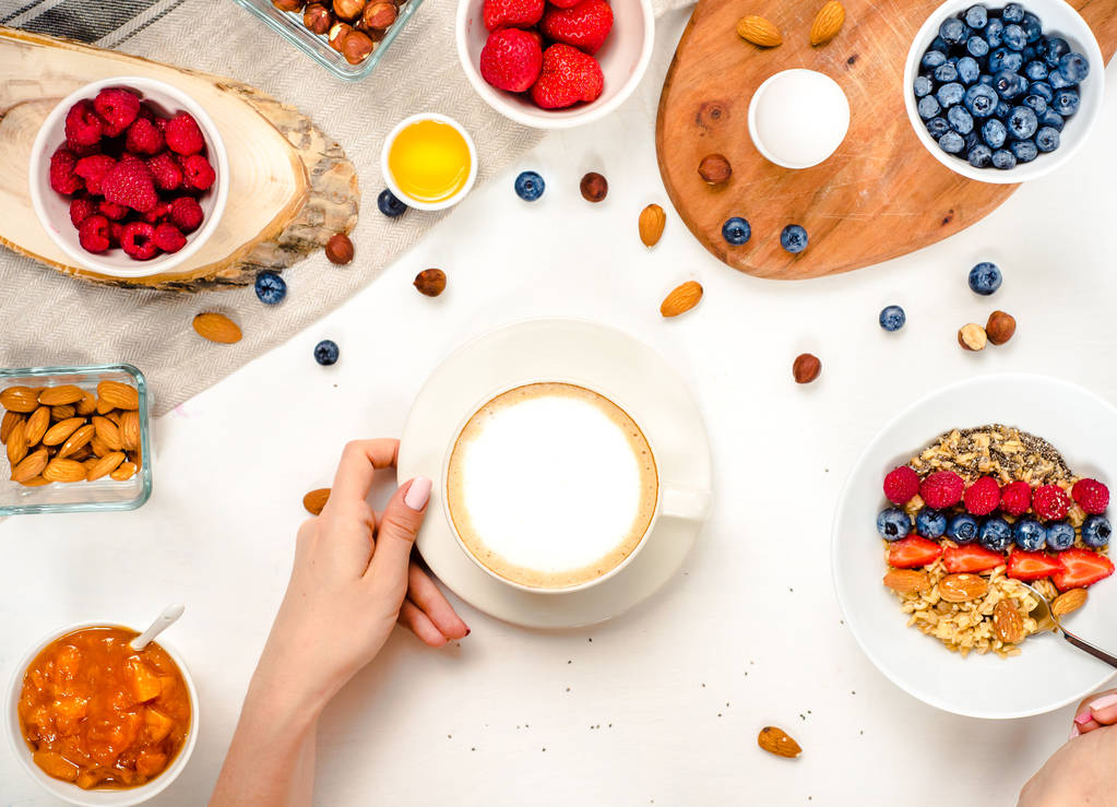 Günaydın - yulaf ezmesi kahve, çilek, yumurta, fındık ile sağlıklı kahvaltı arka plan. Kahve, eller, tutun, cup. Beyaz ahşap gıda arka plan, üstten görünüm - Fotoğraf, Görsel