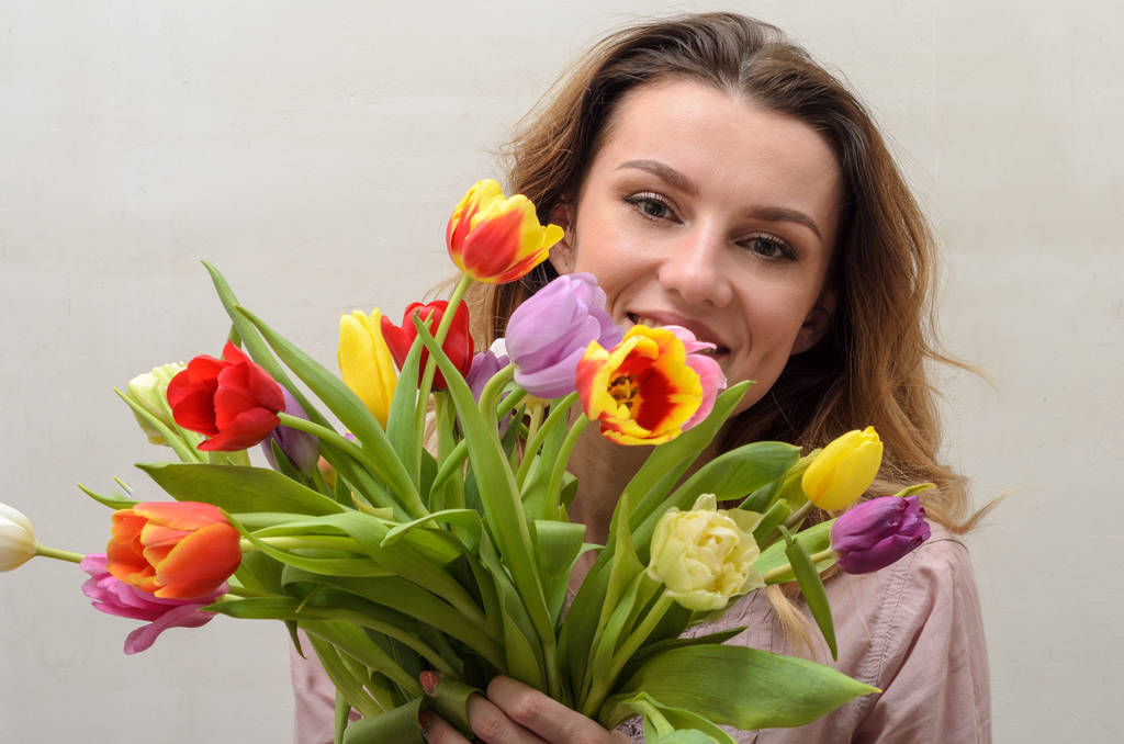 Young charming girl with a bouquet of flowers - multi-colored tulips - Photo, Image
