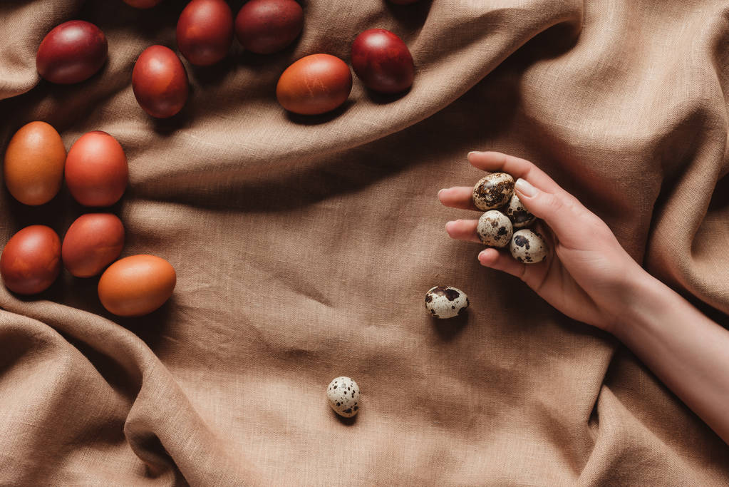 περικοπεί άποψη της χέρι με αυγά ορτυκιών τραπεζομάντιλο με Πασχαλινά αυγά - Φωτογραφία, εικόνα