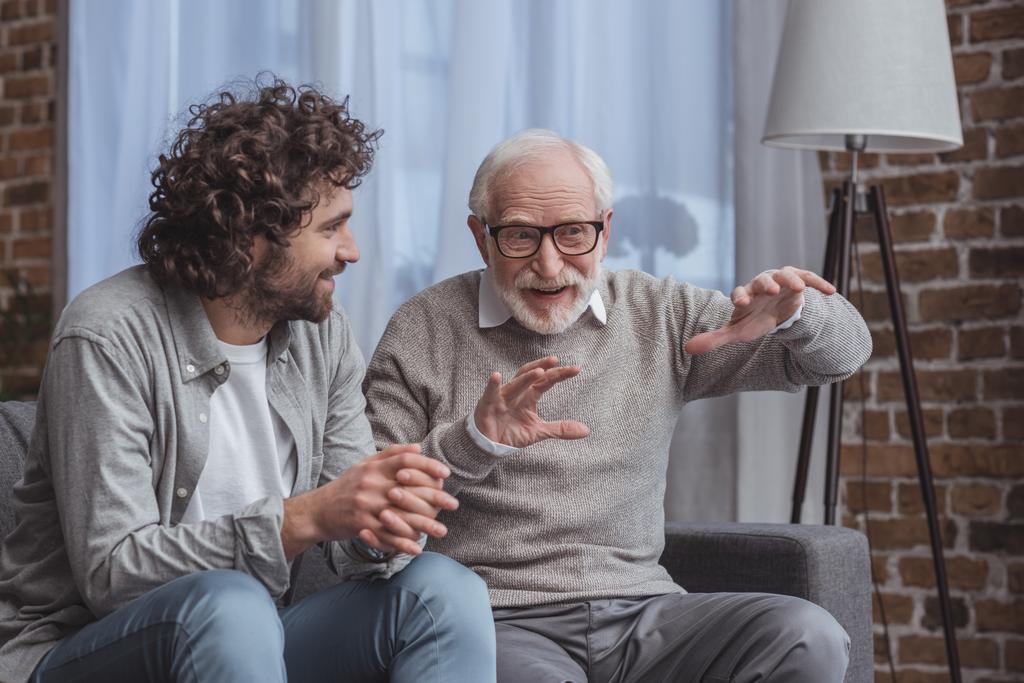 взрослый сын и старший отец разговаривают дома на диване
 - Фото, изображение