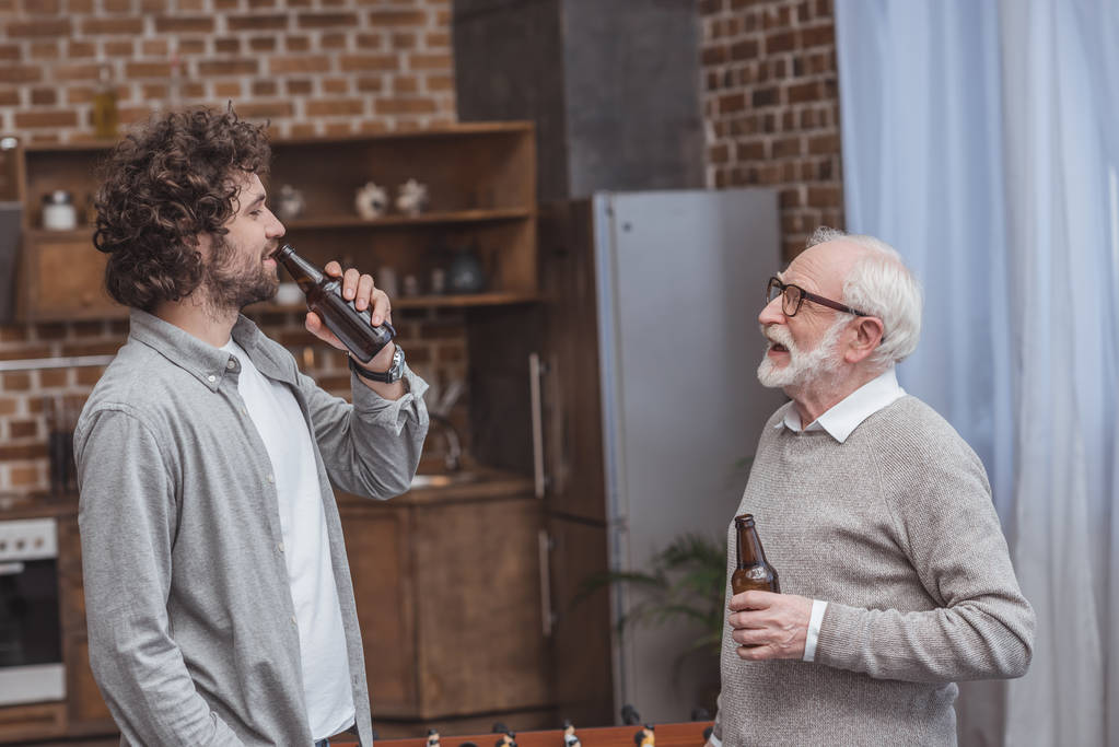 fils adulte et père aîné buvant de la bière et parlant dans la cuisine
 - Photo, image