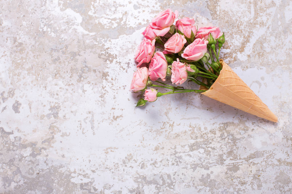 Fresh  pink roses flowers in waffle cone on  grey textured  background. Place for text. Selective focus. - Photo, Image