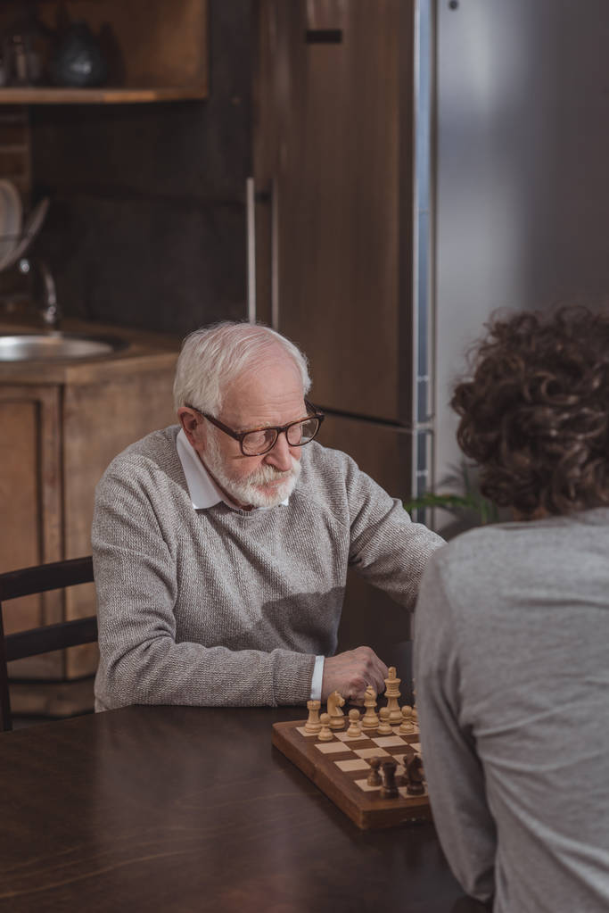 vista de ángulo alto de hijo adulto y padre mayor jugando ajedrez en casa
 - Foto, Imagen