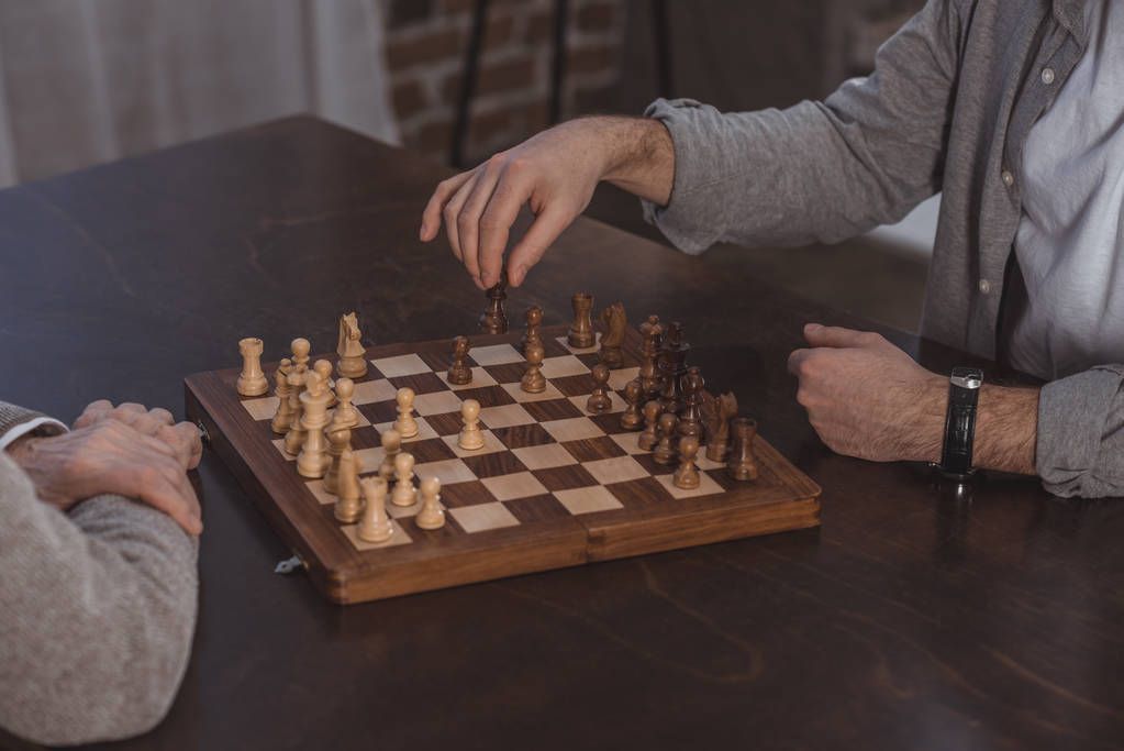 cropped image of adult son and senior father playing chess together at home - Photo, Image