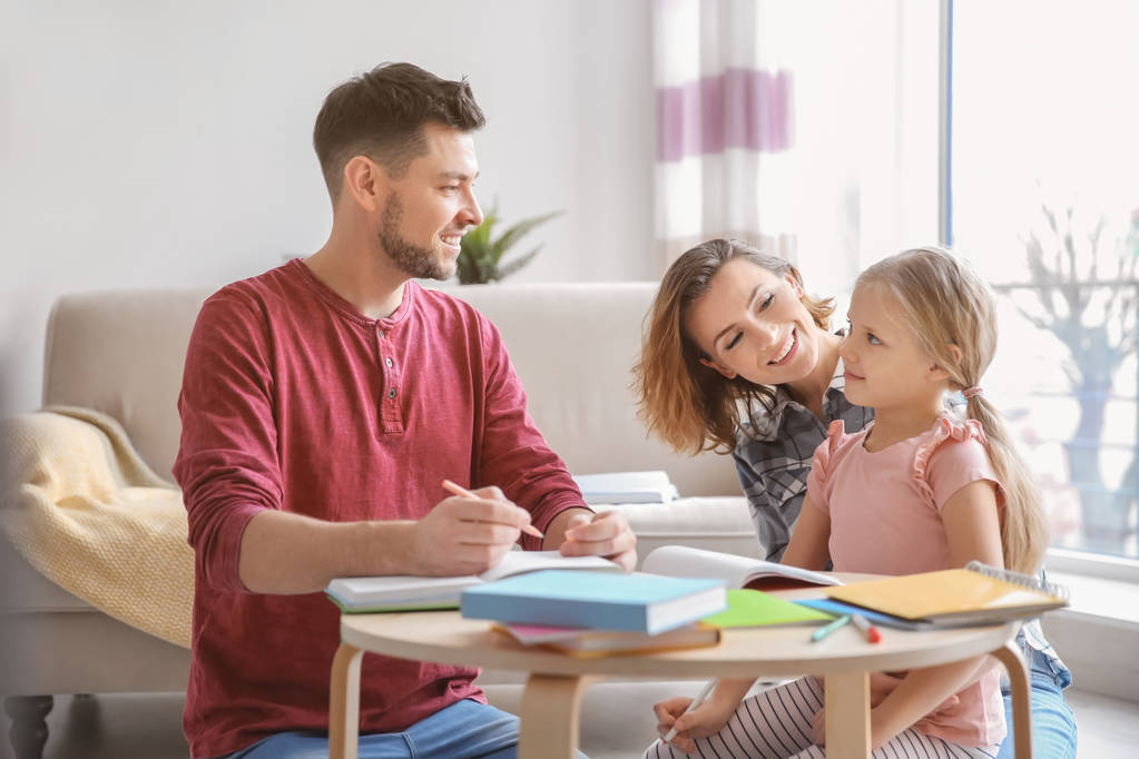 Niña con padres haciendo deberes en casa
 - Foto, Imagen