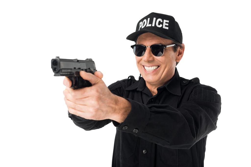 Un policía sonriente apuntando con un arma aislada en blanco
 - Foto, imagen
