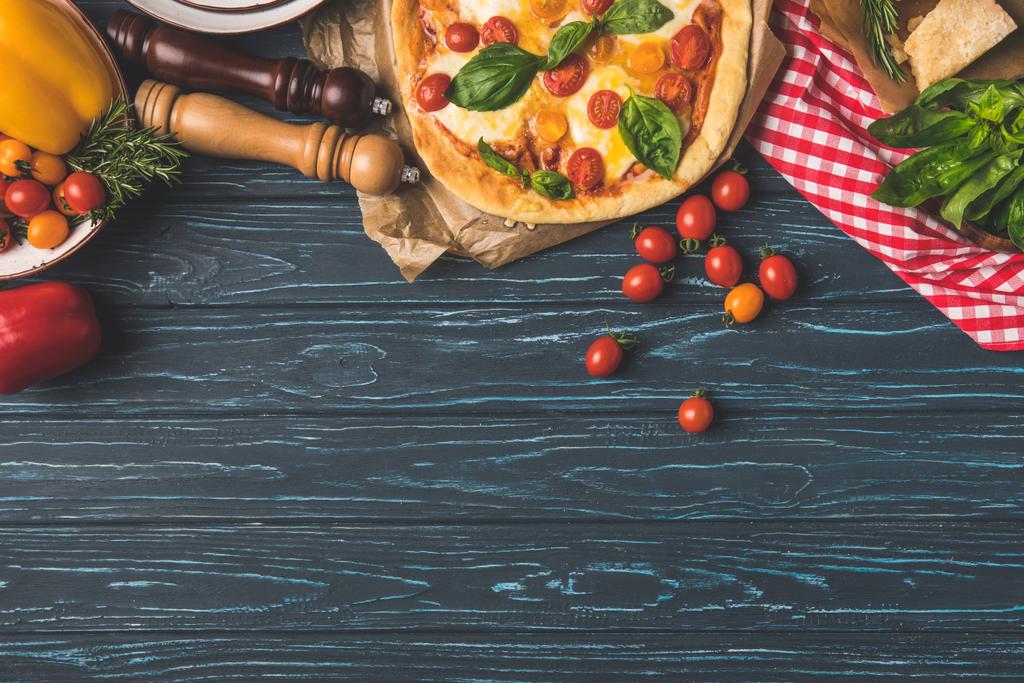 vista superior de pizza saborosa apetitosa e tomates cereja espalhados na mesa
 - Foto, Imagem