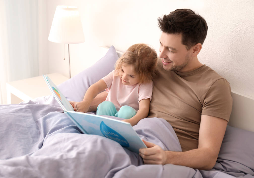 Isä pienen tyttären kanssa lukemassa iltasatua kotona
 - Valokuva, kuva