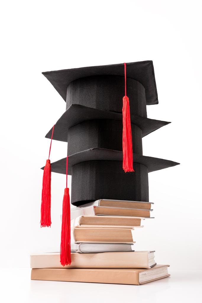 Academische hoeden op stapel boeken geïsoleerd op wit vierkant - Foto, afbeelding