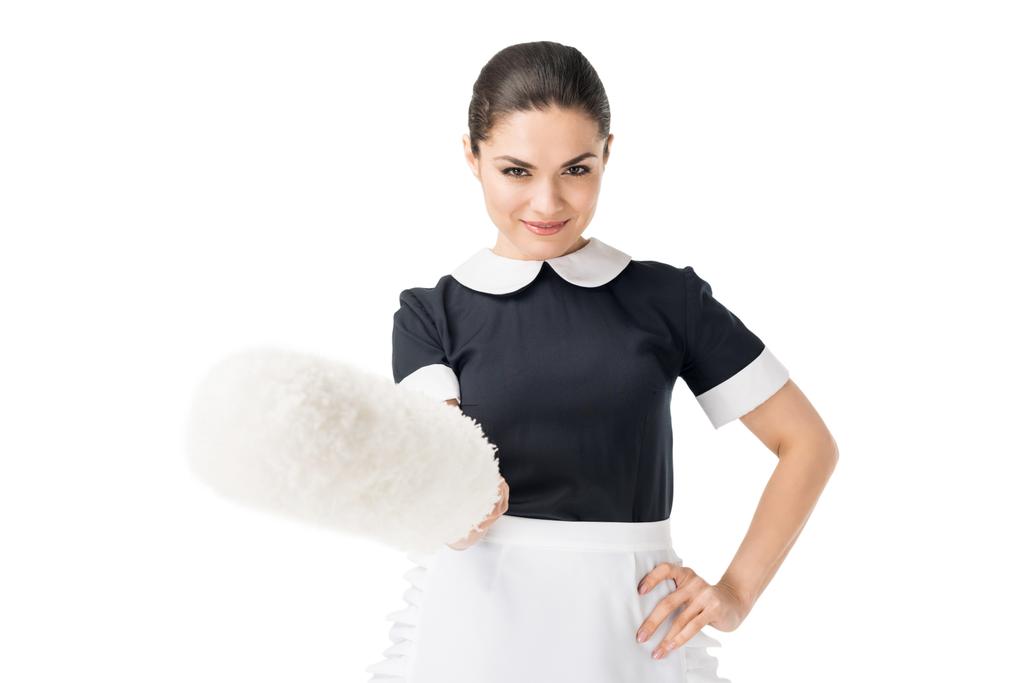 Brunette maid in professional uniform holding duster isolated on white - Photo, Image