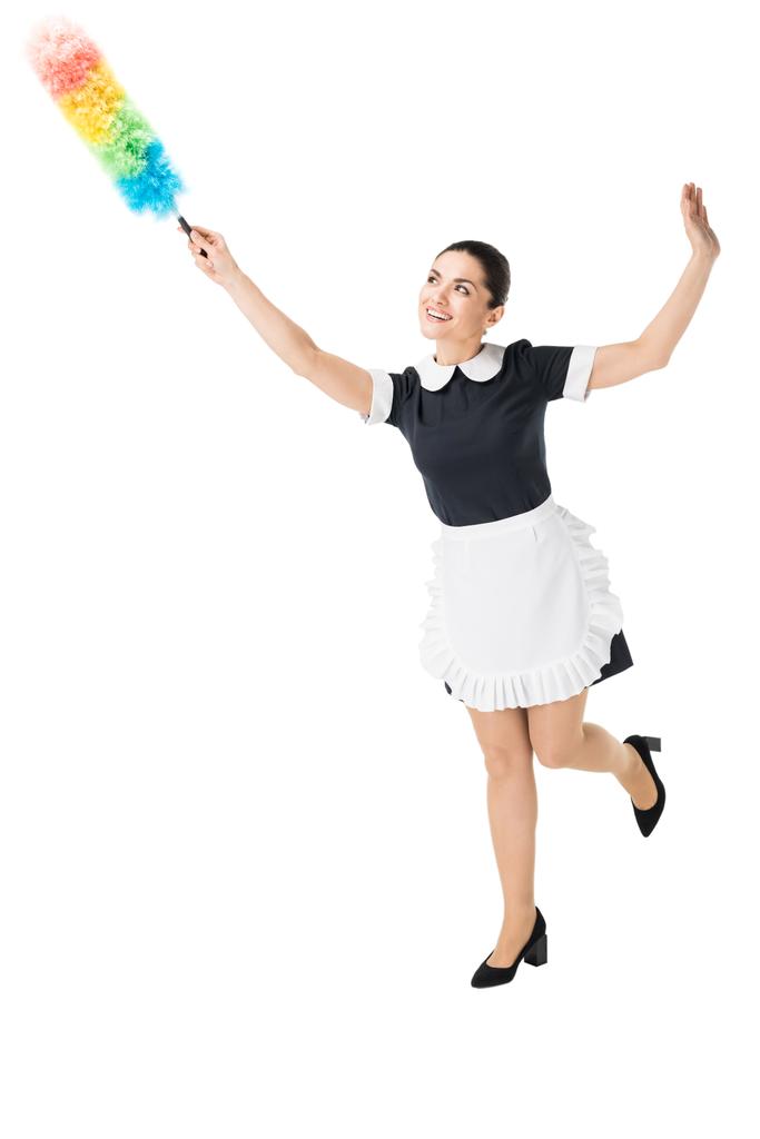 Jovem empregada doméstica em uniforme profissional usando espanador colorido isolado no branco
 - Foto, Imagem