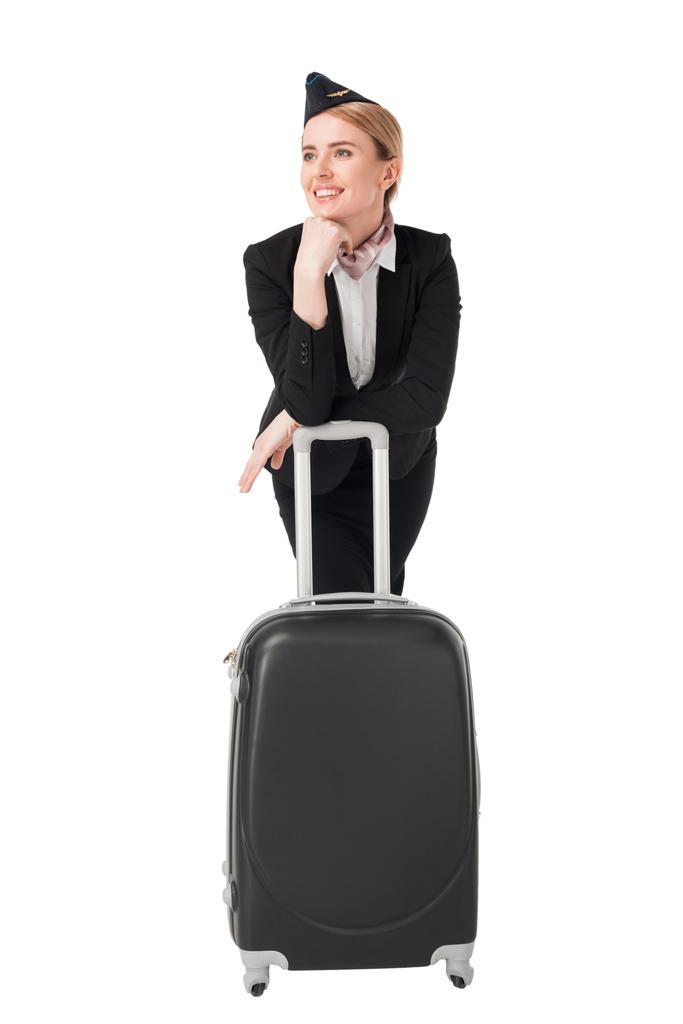 Молода стюардеса в уніформі спирається на валізу ізольовано на білому
 - Фото, зображення