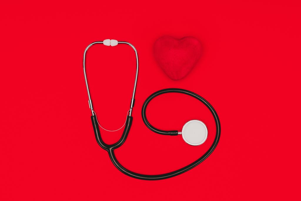 pohled shora stetoskop a červené srdce izolované na červené stolní, koncepce Světový den zdraví - Fotografie, Obrázek