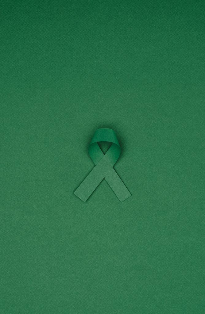 vista de cerca de la cinta de conciencia verde para la escoliosis, símbolo de salud mental aislado en la mesa verde
 - Foto, Imagen