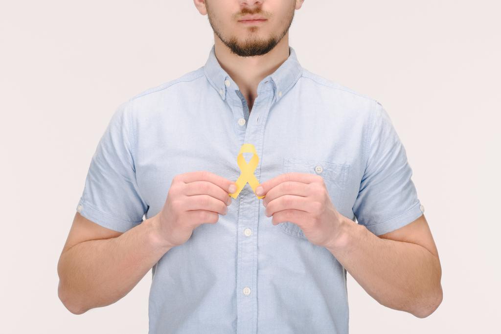 gedeeltelijke weergave van man met Childhood Cancer Awareness geel lint geïsoleerd op wit - Foto, afbeelding