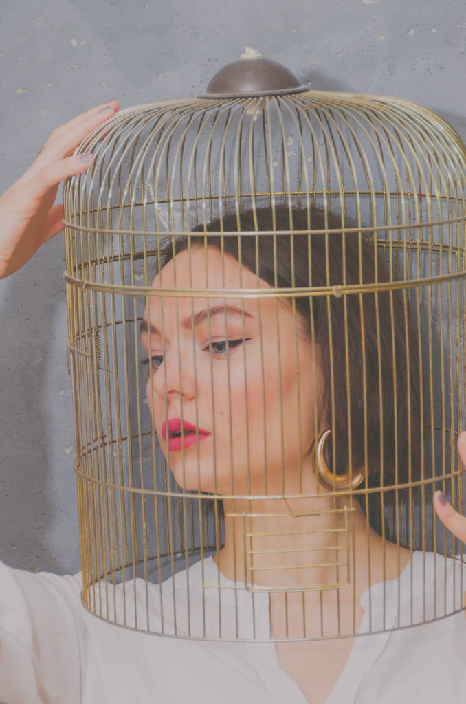 鳥籠の頭の上に灰色の壁の背景に美しい少女 - 写真・画像