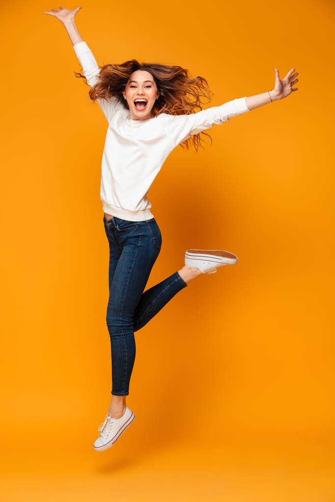 Volledige lengte beeld van Happy brunette vrouw in trui springen - Foto, afbeelding