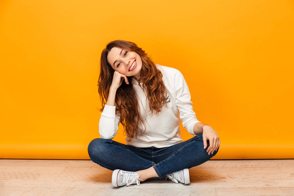 Pleased brunette woman in sweater sitting on the floor - Photo, Image