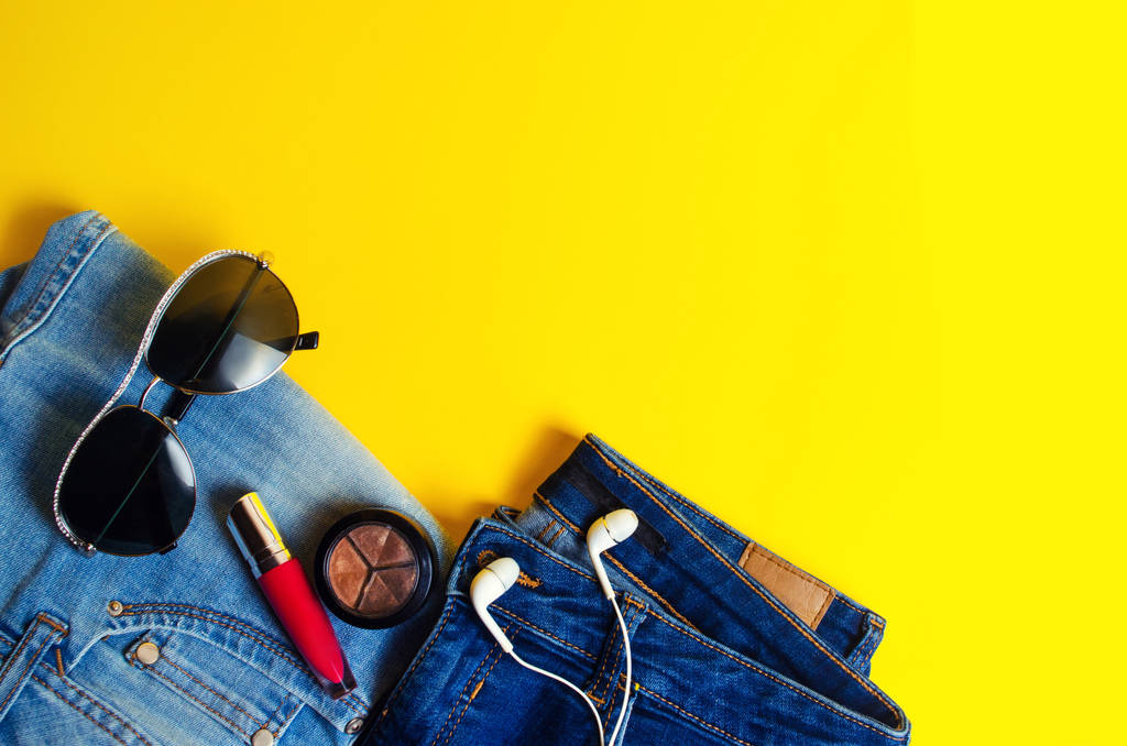 Woman's Things, Elegant Accessories . Jeans, lipstick, glasses, headphones. place for text. yellow background. summer. concept of fashion, style, lifestyle - Photo, Image