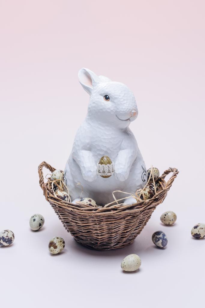 Ester bunny met kwarteleitjes en stro in mand op beige - Foto, afbeelding