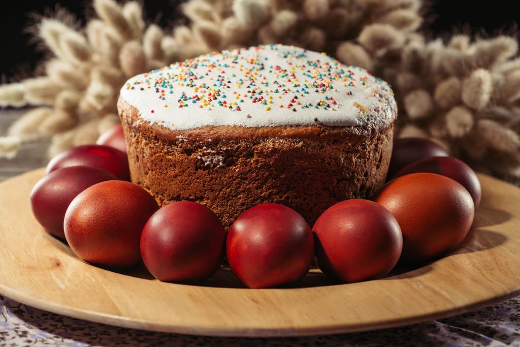 Крупный план окрашенных куриных яиц и сладкого домашнего пасхального торта на тарелке
 - Фото, изображение