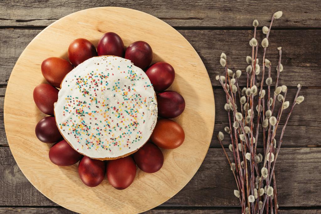 pohled shora malované slepičí vejce kolem domácí velikonoční dort a willow větvičky na dřevěný stůl - Fotografie, Obrázek