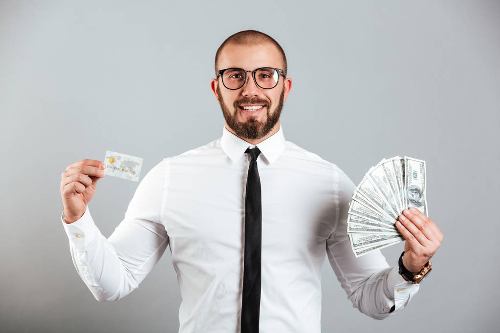 Φωτογραφία του πλούσιου ανθρώπου 30s γυαλιά και ισοπαλία δείχνει πιστωτική κάρτα και - Φωτογραφία, εικόνα
