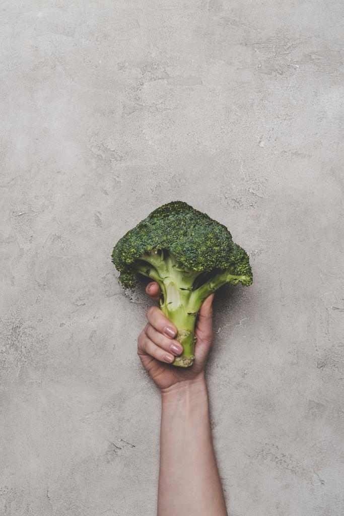 bijgesneden schot van houder van verse biologische broccoli op grijs  - Foto, afbeelding