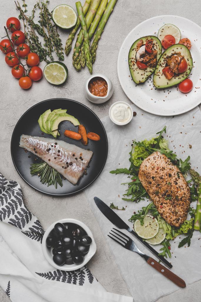 vista superior de platos saludables con pescado, carne y aguacate sobre gris
 - Foto, imagen