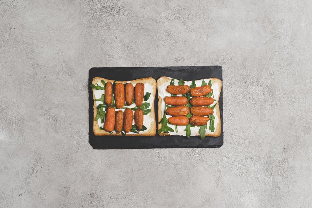 vue de dessus de savoureux sandwichs sains avec roquette et bébé carottes sur ardoise
 - Photo, image