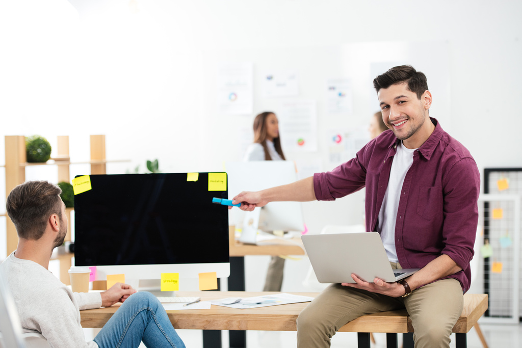 üzletember mutat üres számítógép képernyőjén miközben a munkahelyen dolgozó kolléga hivatalban - Fotó, kép