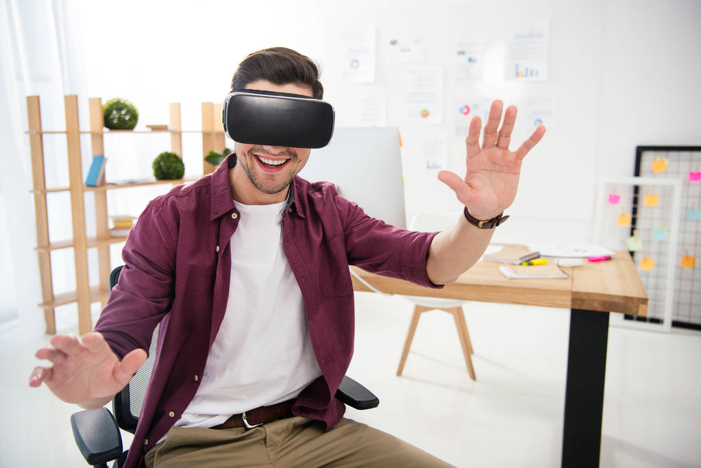 Portret van lachende marketingmanager in virtual reality headset op werkplek op kantoor - Foto, afbeelding