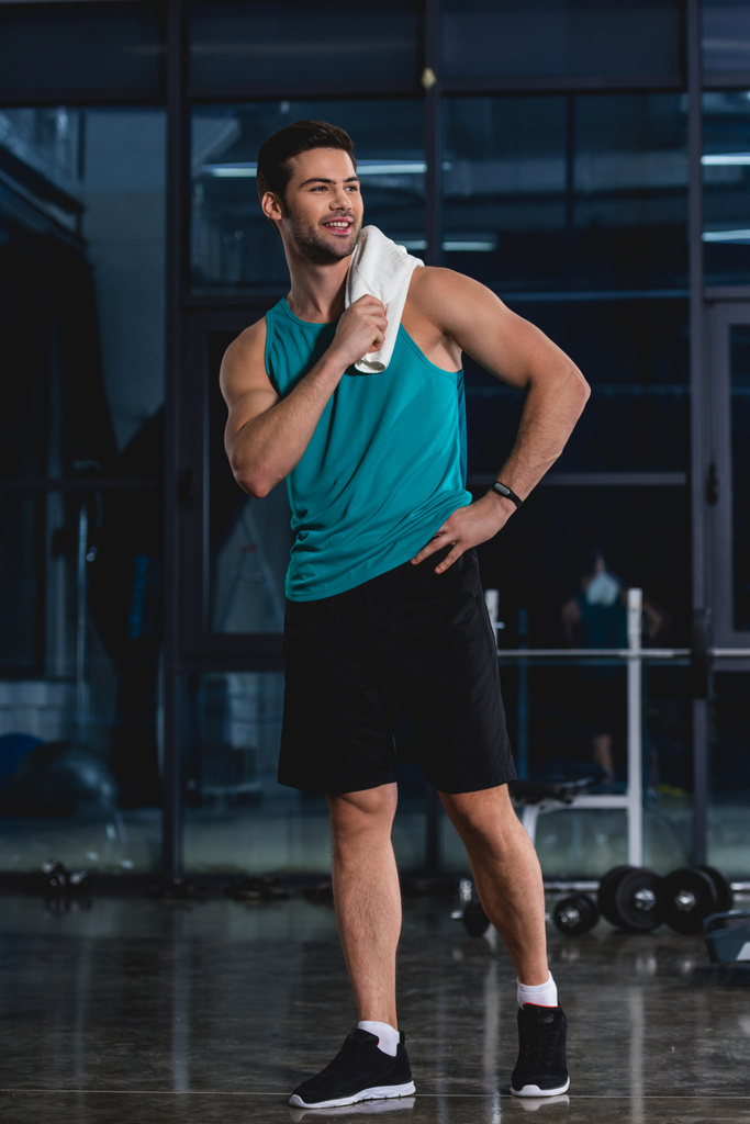 улыбающийся спортсмен, стоящий с полотенцем после тренировки в тренажерном зале
 - Фото, изображение