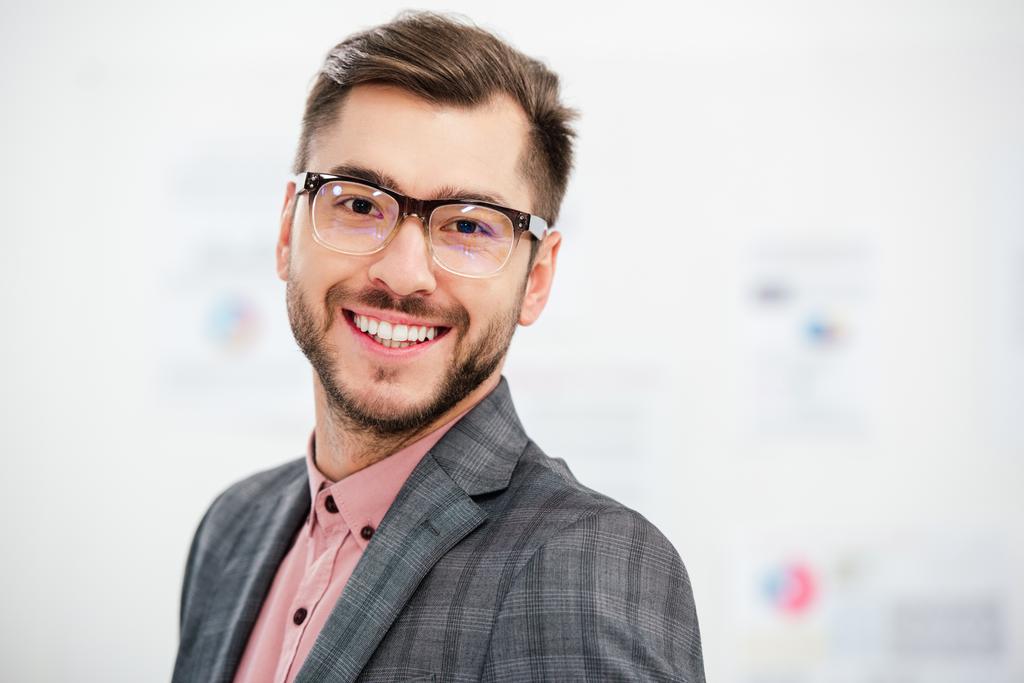 портрет улыбающегося бизнесмена в костюме и очках, смотрящего в камеру
 - Фото, изображение