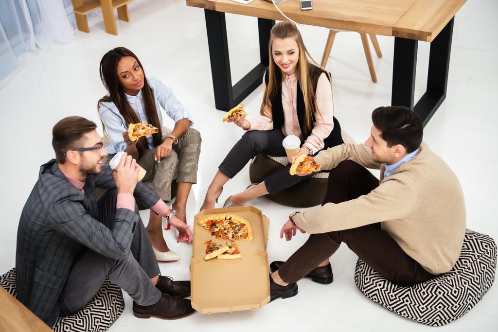 vista de ángulo alto de la gente de negocios multiétnicos comiendo pizza en la oficina
 - Foto, Imagen