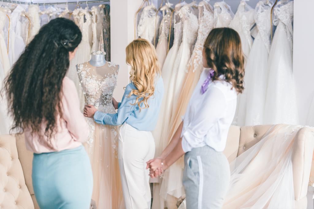 Happy bride and bridesmaids trying on dresses in wedding atelier - Photo, Image