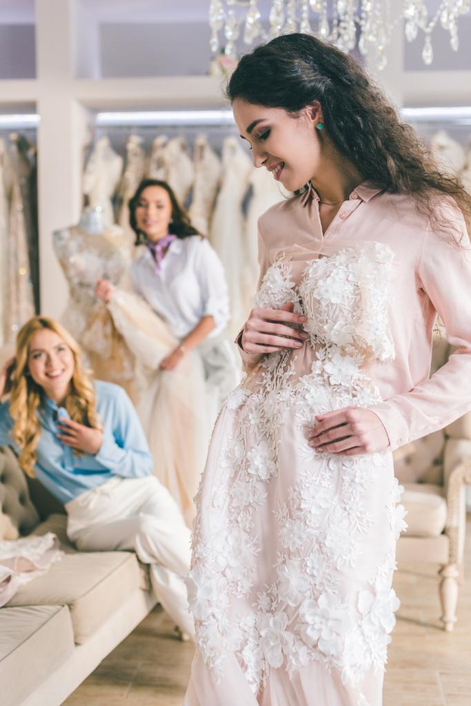 Bride with lace dress and bridesmaids in wedding salon - Photo, Image