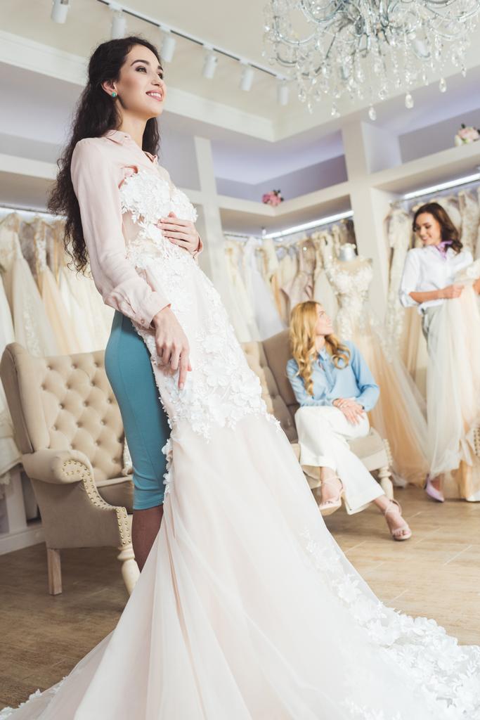  Bruid met lace jurken en bruidsmeisjes in wedding atelier - Foto, afbeelding