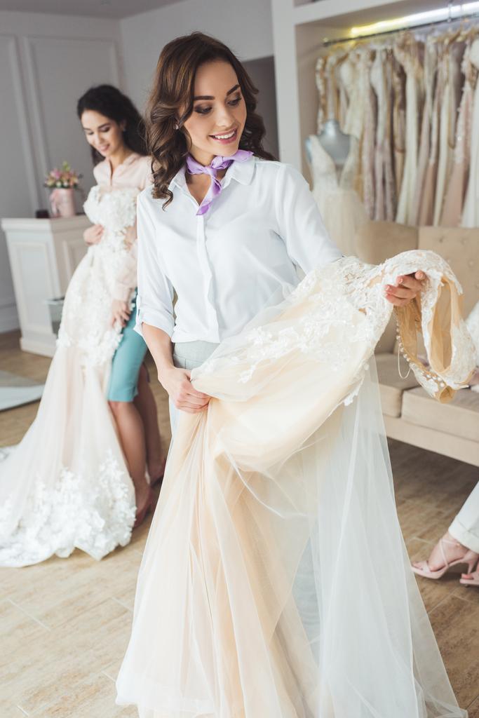 Happy women choosing wedding dresses in wedding fashion shop - Photo, Image