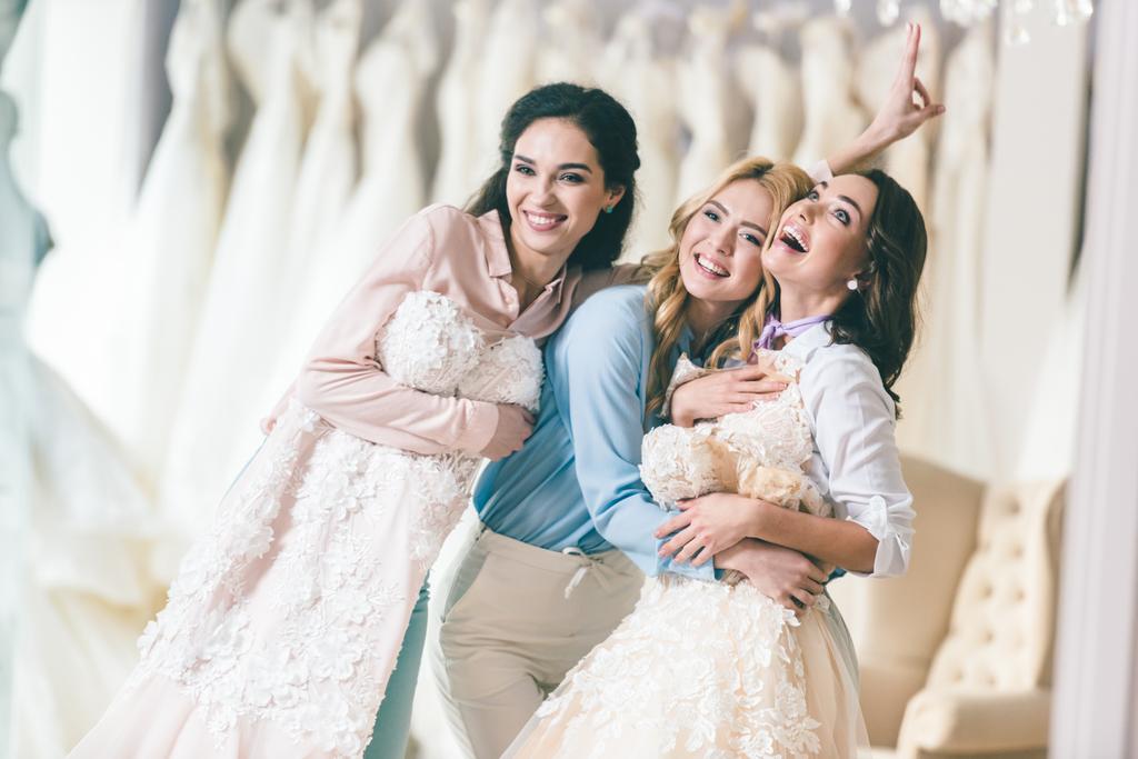 Smiling women with wedding dresses in wedding atelier - Photo, Image