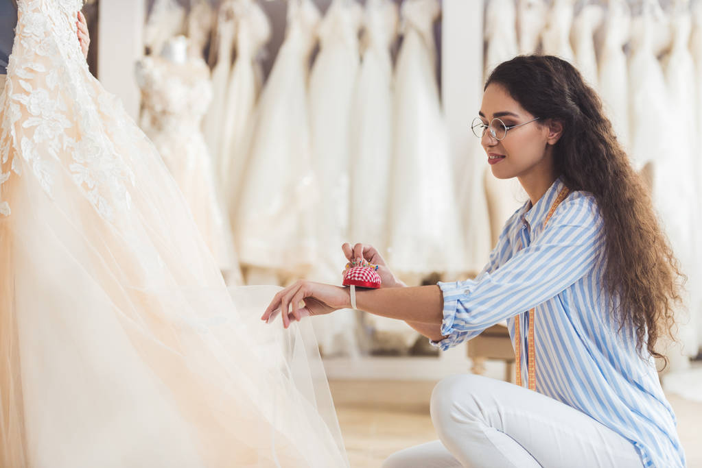 Näherin arbeitet im Hochzeitsatelier an einem schönen Kleid - Foto, Bild