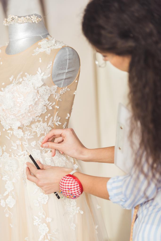 Costurera trabajando por hermoso vestido en atelier de boda
 - Foto, Imagen