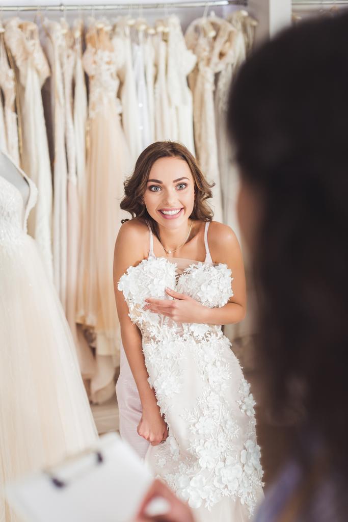 Beautiful bride trying on dress in wedding fashion shop - Photo, Image