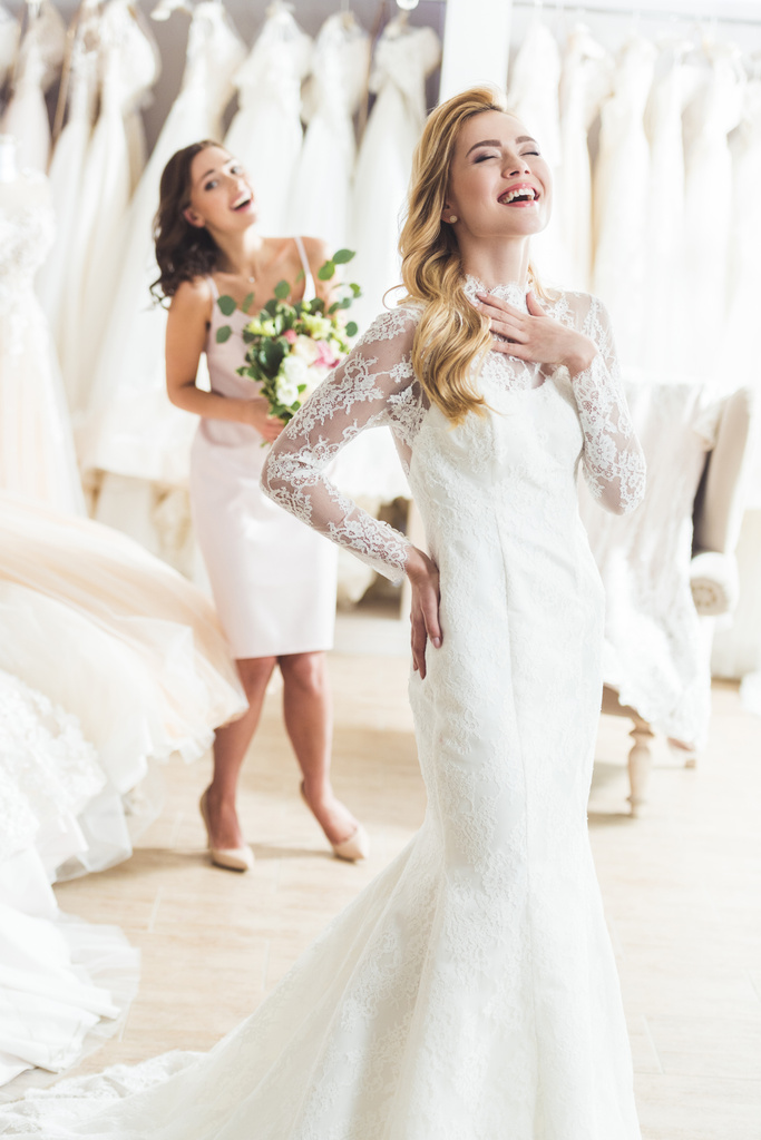 Lachende Braut und Brautjungfer im Geschäft für Hochzeitsmode - Foto, Bild