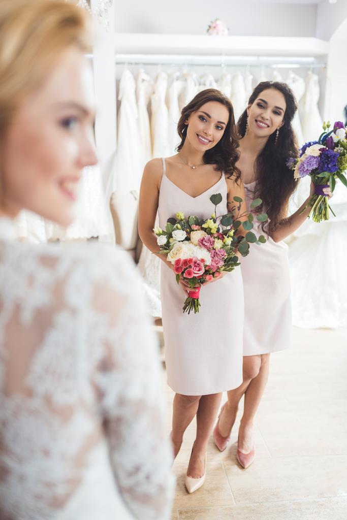 Счастливая невеста и подружки невесты с цветами в свадебном салоне
 - Фото, изображение