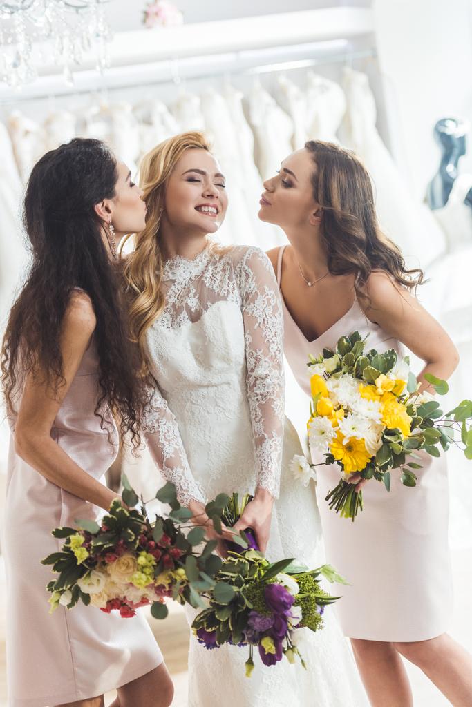 Aantrekkelijke vrouwen in trouwjurken zoenen in huwelijk salon - Foto, afbeelding