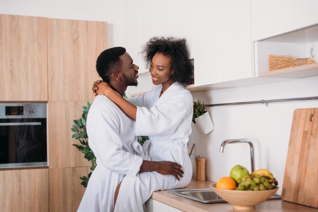 Smiling african american couple hugging in kitchen - Photo, Image