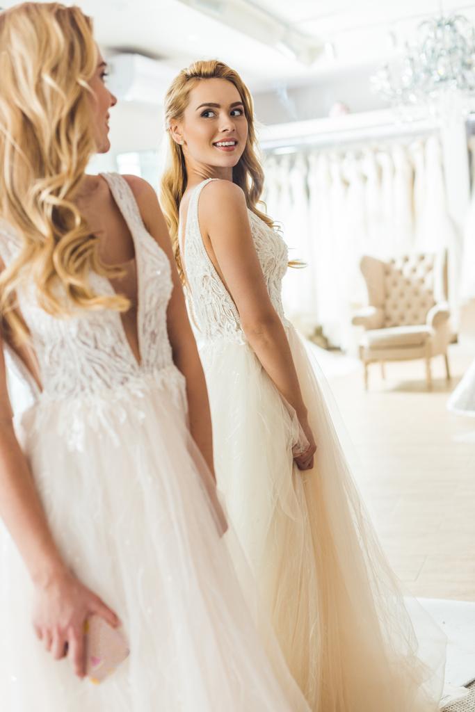 Молода наречена в білій сукні від дзеркала в магазині весільної моди
 - Фото, зображення