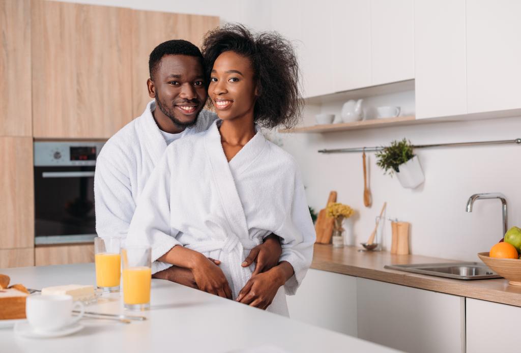 Νέος, χαμογελαστός αφρικανική αμερικανική ζευγάρι αγκαλιάζει στην κουζίνα - Φωτογραφία, εικόνα